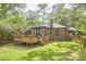 Backyard view of a brick home featuring a wooden deck, grassy lawn, and privacy fence at 1307 Arnette Ave, Durham, NC 27707