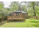 Brick house with a wooden deck, grassy lawn, and surrounding trees create a peaceful backyard at 1307 Arnette Ave, Durham, NC 27707