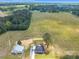 Aerial shot of a farmhouse and metal barn, nestled amid green fields and forests under a vast blue sky at 1347 Crocker Rd, Smithfield, NC 27577