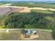 Aerial view of a country property with a home and metal barn, nestled amidst fields and woodlands under a clear sky at 1347 Crocker Rd, Smithfield, NC 27577