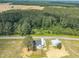An aerial view of a charming property with a house and a metal barn enveloped by dense woods and neighboring farmlands at 1347 Crocker Rd, Smithfield, NC 27577