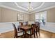 Formal dining area showcasing wainscoting, a classic chandelier, and a large window for ample natural light at 1437 Chelton Oaks Pl, Raleigh, NC 27614