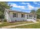 Charming white home featuring a brick facade, decorative shutters, manicured landscaping, and inviting front porch at 1732 Green Pace Rd, Zebulon, NC 27597