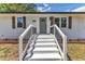 Inviting front porch with white stairs leading to a charming green door, surrounded by manicured landscaping at 1732 Green Pace Rd, Zebulon, NC 27597