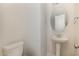 A powder room features a pedestal sink, round mirror, and a white toilet at 175 Trescott St, Smithfield, NC 27577
