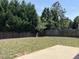 Fenced backyard with mature trees surrounding the perimeter and a concrete patio area at 2018 Groundwater Pl, Raleigh, NC 27610