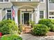 Inviting front porch with brick steps, lush greenery, and an American flag, adding charm to the home's entrance at 204 Rossburn Way, Chapel Hill, NC 27516
