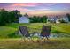 Scenic backyard view with two chairs overlooking a tranquil pond at sunset at 232 Kanewind Ter, Apex, NC 27523