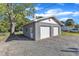 Detached two car garage in gray with white doors, nestled under a large shade tree at 2501 Ferrell Rd, Durham, NC 27704