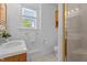 Bright bathroom featuring tiled walk-in shower, white ceramic sink, and wood cabinets at 2910 Dove Ln, Raleigh, NC 27604