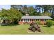 Charming brick home featuring a lush lawn and garden beds bursting with colorful flowers at 2910 Dove Ln, Raleigh, NC 27604