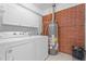 Bright laundry room with brick accent wall, tiled floor and storage cabinets at 2910 Dove Ln, Raleigh, NC 27604