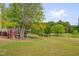 Spacious backyard featuring a red chicken coop surrounded by lush green lawn and mature trees at 303 Crooked Meadow Ln, Hillsborough, NC 27278