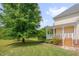The home features a charming covered porch with stairs leading down to the grassy backyard at 303 Crooked Meadow Ln, Hillsborough, NC 27278
