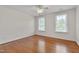 Bright, airy bedroom featuring hardwood floors, neutral paint, and abundant natural light from the two windows at 303 Crooked Meadow Ln, Hillsborough, NC 27278