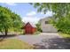Exterior of a two-car garage and outbuilding with an expansive driveway surrounded by mature trees at 303 Crooked Meadow Ln, Hillsborough, NC 27278
