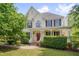 Stately two-story home featuring a manicured lawn, charming front porch, and a red front door at 303 Crooked Meadow Ln, Hillsborough, NC 27278