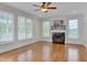 Light-filled living room featuring a cozy fireplace, hardwood floors, and large windows at 303 Crooked Meadow Ln, Hillsborough, NC 27278
