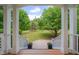 Covered porch view of green lawn with mature trees and landscaping at 303 Crooked Meadow Ln, Hillsborough, NC 27278