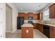 Modern kitchen with wooden cabinets, black appliances, a central island, and tile floors at 309 Windy Peak Loop, Cary, NC 27519