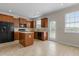 Open kitchen with wood cabinets, a black refrigerator, a central island, and tile flooring at 309 Windy Peak Loop, Cary, NC 27519