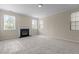 Sunlit living room with a fireplace, plush carpet, and windows at 309 Windy Peak Loop, Cary, NC 27519
