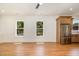 Open living room with white walls, hardwood floors, large windows and a stainless steel refrigerator at 310 W Club Blvd, Durham, NC 27704