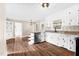 Light and open kitchen featuring white cabinets, granite countertops, stainless steel appliances, wood flooring, and island seating at 311 Nc 56, Louisburg, NC 27549