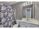 Well-lit bathroom features vanity with sink, commode and a shower with decorative floral curtain at 3315 Swinford Ct, Raleigh, NC 27604