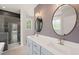 Bathroom with double sinks, granite countertops, decorative mirrors, and a tiled shower with glass door at 380 Pilot Ridge Rd, Zebulon, NC 27597