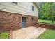 Back exterior with brick and siding, featuring a door leading to a patio with steps and greenery at 4006 Daniel Rd, Durham, NC 27703