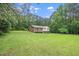 A charming home with a brick facade sits nestled in a lush green lawn, surrounded by towering trees at 4006 Daniel Rd, Durham, NC 27703