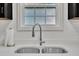 Close-up of stainless steel sink, paper towel holder, and quartz countertop in kitchen with window at 407 Collier St, Smithfield, NC 27577