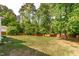Large backyard is surrounded by lush trees and a wooden fence at 4109 Huckleberry Dr, Raleigh, NC 27612