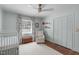 Bedroom featuring a white crib, chair, closet with white doors, and wall decoration with books displayed on shelves at 4109 Huckleberry Dr, Raleigh, NC 27612