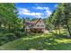 View of the two-story home featuring a brick foundation, deck, large yard, and mature trees at 4900 North Hills Dr, Raleigh, NC 27612