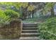 A tiered backyard featuring brick steps, privacy shrubbery and mature trees, offering a serene escape at 4900 North Hills Dr, Raleigh, NC 27612
