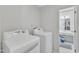Well-lit laundry room featuring modern, white, front-loading washer and dryer units at 4900 North Hills Dr, Raleigh, NC 27612