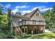 Exterior view showcasing a charming elevated deck, a brick patio, mature trees, and a manicured lawn at 4900 North Hills Dr, Raleigh, NC 27612