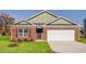 Charming brick home features a well-manicured lawn and an attached garage at 493 Lochalsh Dr, Gibsonville, NC 27249