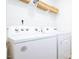 Well-lit laundry room features white washer and dryer with storage shelf above at 493 Lochalsh Dr, Gibsonville, NC 27249