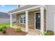 Inviting front porch with stone accents, white pillars, and a dark-colored front door at 506 Lochalsh Dr, Gibsonville, NC 27249