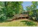 Backyard featuring a wood deck with stairs leading to a grassy lawn surrounded by trees at 5100 Yale Ct, Graham, NC 27253