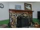 Rustic stone fireplace with a wood mantel, artwork, and decorative accessories at 5100 Yale Ct, Graham, NC 27253