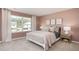A serene bedroom with a white bed frame, large window, and blush-colored walls at 511 Lochalsh Dr, Gibsonville, NC 27249