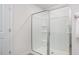 A sleek, glass-enclosed shower with chrome hardware in an all-white modern bathroom at 511 Lochalsh Dr, Gibsonville, NC 27249