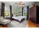 Inviting bedroom with a hardwood floor, decorative ceiling fan, windows with blinds, and accent furniture at 518 S Main St, Wake Forest, NC 27587