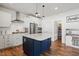 Open-concept kitchen boasts stainless appliances, white cabinets, subway tile backsplash, and a large navy blue island at 521 Glenwyck Ct, Fuquay Varina, NC 27526