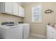 Laundry room featuring white cabinets, modern washer and dryer units, and natural light from a large window at 624 Meadowgrass Ln, Wake Forest, NC 27587