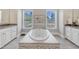 Elegant bathroom featuring a soaking tub with views of the landscaped yard through two windows at 7304 Hasentree Club Dr, Wake Forest, NC 27587